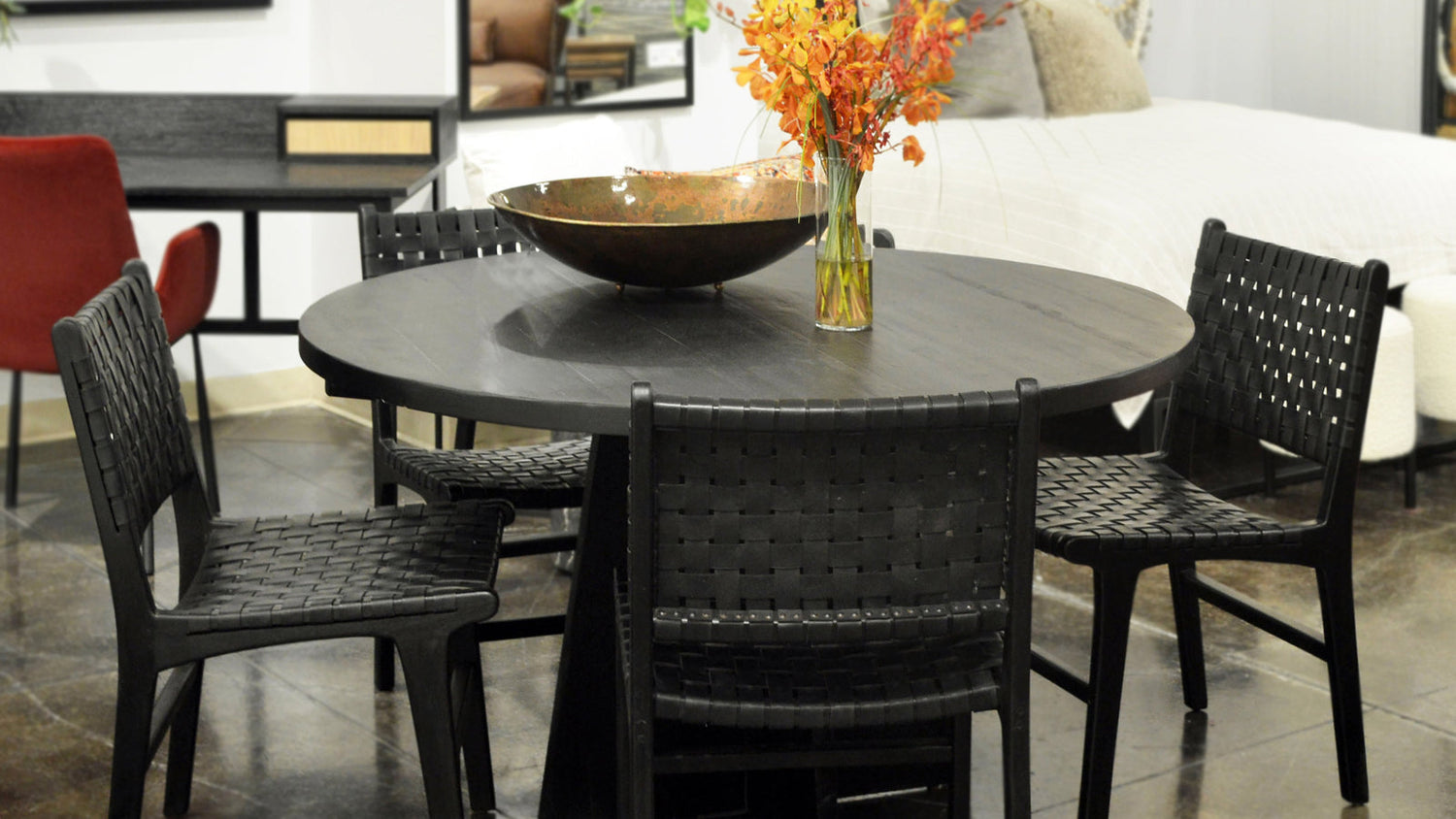 Black woven leather dining chairs around a round dining table in a layered room