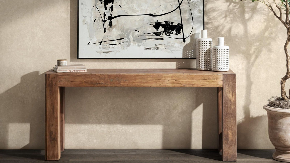 Natural reclaimed wood console table styled with abstract art, white ceramic vases, and a potted tree
