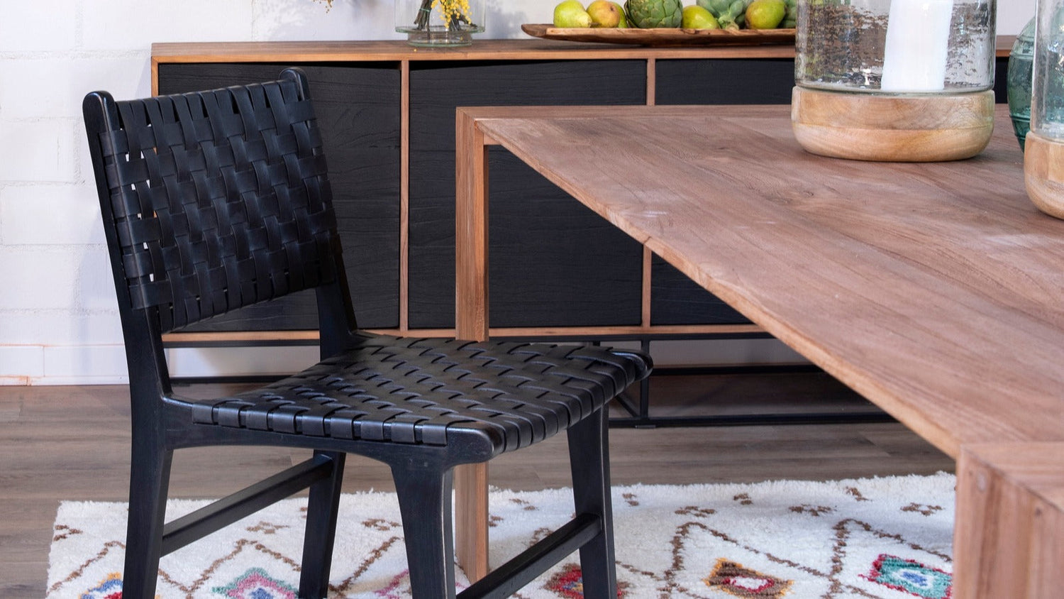 Dining room mixing a natural wood table with a black woven dining chair and a dark sideboard
