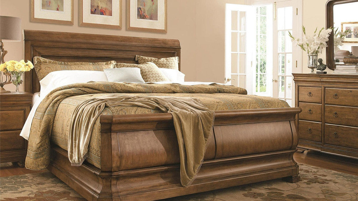 Louis Philippe solid wood sleigh bed styled with warm neutral bedding, nightstands, and a coordinating dresser