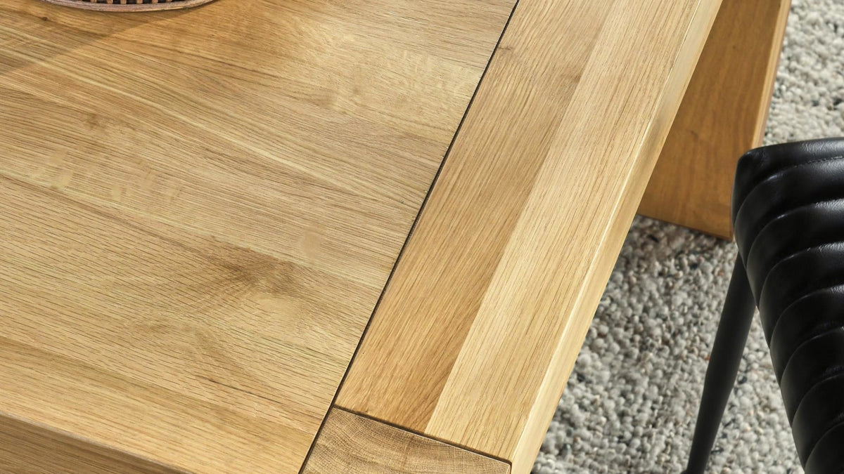 Natural oak Parsons dining table styled with a woven tray, black chair and textured rug